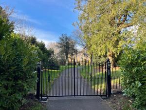 a black gate in a park with a driveway at The Rectory Lacock - Boutique Bed and Breakfast in Lacock