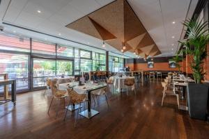 a dining room with tables and chairs and windows at DoubleTree by Hilton Paris Boulogne in Boulogne-Billancourt