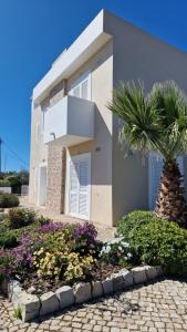 a house with a palm tree in front of it at Roots Villa - Casa das Árvores in Cabanas de Tavira
