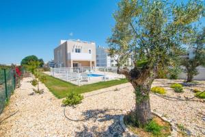 a tree in front of a building with a pool at Roots Villa - Casa das Árvores in Cabanas de Tavira
