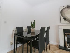 a black dining room table with black chairs and a plant at 42 Ynys Y Nos in Neath