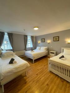 a bedroom with two beds and two windows at Riverside Guesthouse in Charlestown