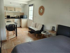 a bedroom with a bed and a kitchen with a table at La Plénitude in Le Thor