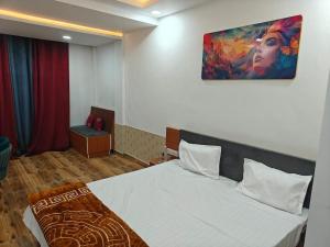 a bedroom with a bed with a painting on the wall at The R B Tower in Unnāo