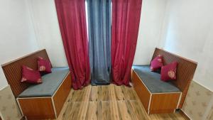 two benches in a room with red curtains at The R B Tower in Unnāo