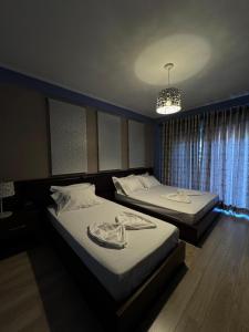two beds in a bedroom with a chandelier at Dreams Hotel in Gjirokastër