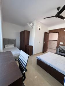a bedroom with two beds and a table and a ceiling fan at Sukoon Stays in Noida