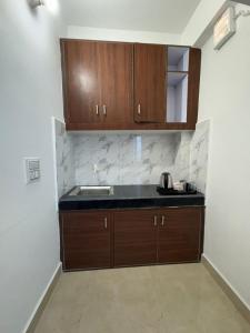 a kitchen with a sink and wooden cabinets at Sukoon Stays in Noida
