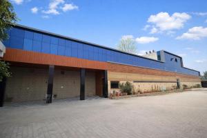 a large brick building with a blue roof at Hotel Sunrahi in Nagīna
