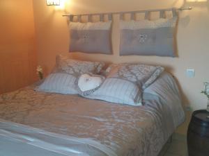 a bed with a heart pillow and pillows on it at Le Logis du Livier in Saint-Georges-sur-Layon