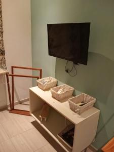a tv on top of a shelf with three baskets at Charmant studio à Sfax in Sfax