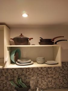 a kitchen shelf with pots and pans on it at Charmant studio à Sfax in Sfax