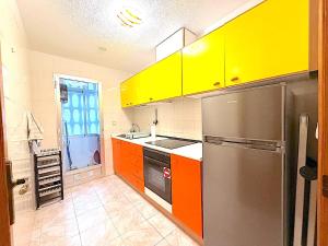 a kitchen with yellow and orange cabinets and a refrigerator at Santa Pola port in Santa Pola