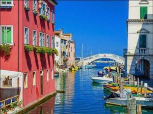 a canal with boats in the water between buildings at Maison Belle Vue in Chioggia