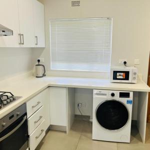 a kitchen with a washing machine under a counter at 219 Contours Luxury Apartment in Victoria Falls