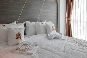 a bed with white sheets and pillows in a bedroom at Dwija Hotel & Suite in Pattaya South +39 photos