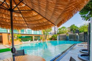 a large swimming pool with a straw umbrella at Dwija Hotel & Suite in Pattaya South