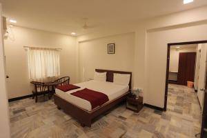 a bedroom with a bed and a table and a mirror at Hotel Rayas in Kumbakonam