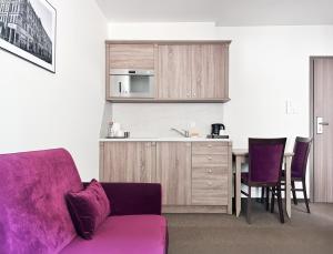 a living room with a purple couch and a kitchen at WILla Medica in Poznań
