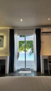 a bedroom with a view of the beach through a sliding glass door at Coral Reef Holidays in Tioman Island