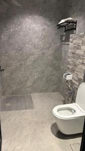 a bathroom with a toilet and a stone wall at المكان الخاص للشقق المخدومة - أقتصادي in Unayzah