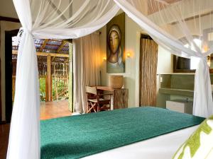 a bedroom with a bed with a green comforter at Casa Felina in Ilha de Boipeba