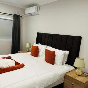 a bedroom with a large bed with orange and white pillows at 219 Contours Luxury Apartment in Victoria Falls