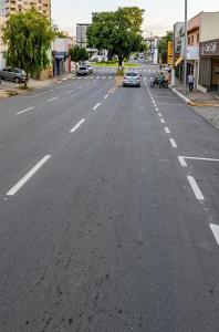 an empty street with a car driving down the road at Quarto individual Aconchego in Divinópolis +4 photos