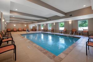 a pool in a hotel lobby with chairs and tables at Hampton Inn & Suites Harvey New Orleans Westbank in Harvey
