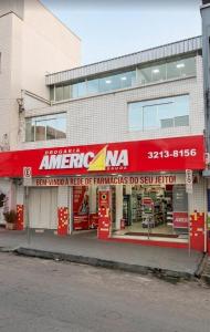 a store with a red sign on the side of a building at Quarto individual Aconchego in Divinópolis