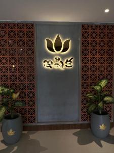 a sign on a wall with two potted plants at ishika grand in Secunderabad