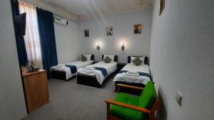 a room with two beds and a green chair at Garden Palace Khiva in Khiva