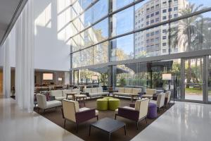 a lobby with chairs and tables and large windows at Hilton Barcelona in Barcelona