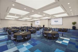 a conference room with tables and chairs and a screen at Hilton Barcelona in Barcelona