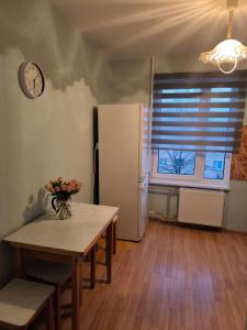 a kitchen with a table and a refrigerator and a clock at Central Point Apartments in Rēzekne
