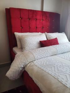 a large bed with a red headboard and white pillows at Azure View Studio with pool in Kiahuria +9 photos