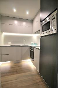 a kitchen with white cabinets and a microwave at RestOnDouro Oporto Studio in Valbom