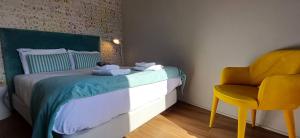 a small bedroom with a bed and a yellow chair at RestOnDouro Oporto Studio in Valbom