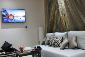 a living room with a couch and a tv on a wall at Appartement Mogador in Casablanca