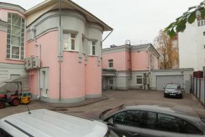 un coche aparcado en un estacionamiento frente a una casa rosa en Gorky Hotel, en Nizhny Novgorod