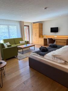 a bedroom with a bed and a couch and a tv at Landhaus Langeck in Münstertal
