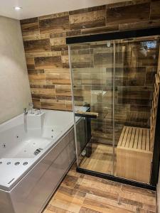 a bathroom with a tub and a glass shower at Vila Bašić Vlašić MEDO Spa Apartman Sauna & Jacuzzi in Vlasic