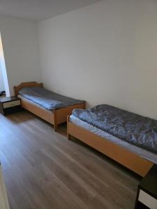 two beds in a room with wooden floors at Center- Podčetrtek in Podčetrtek