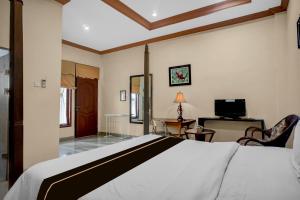 a bedroom with a bed and a desk and a television at Collection O near University of Sumatera Utara formerly Huber Apartment in Medan