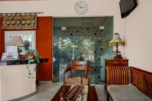 a living room with a table and a clock on the wall at Collection O near University of Sumatera Utara formerly Huber Apartment in Medan