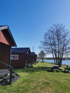 a row of huts next to a body of water at Stuga1-6 Dalskärs camping Badrum i Servicehus in Bergkvara