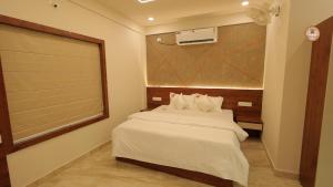 a bedroom with a white bed with a window and a fan at Bekal Gate Residency in Kotikulam