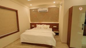a bedroom with a bed with white sheets and a window at Bekal Gate Residency in Kotikulam