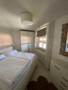 a bedroom with a white bed and a window at Seeloge mit Dachterrasse direkt am Westhafen in Hagnau am Bodensee in Hagnau