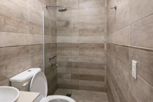 a bathroom with a toilet and a glass shower at Departamento moderno, equipado full en vicente López ,ubicacion inmejorable a 100 metros del tren in Florida